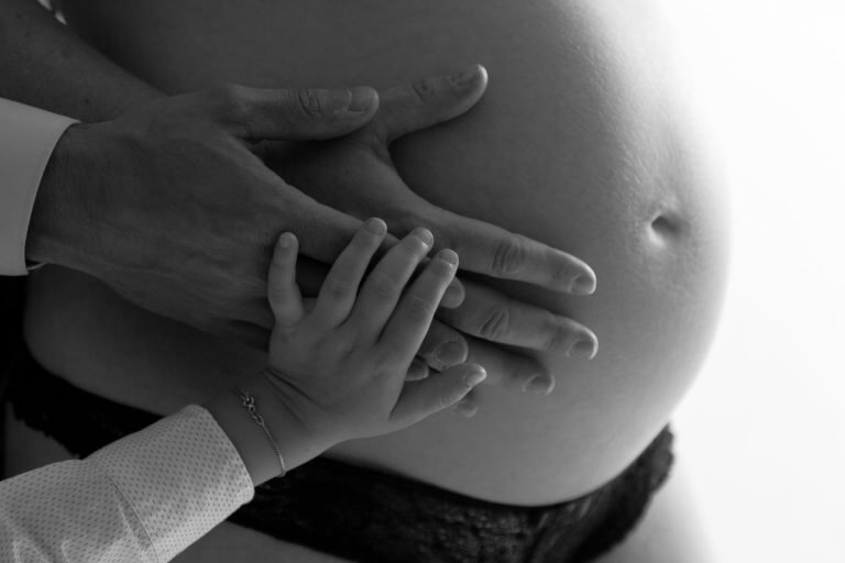 photo du ventre d'une femme enceinte avec les mains du grand frère