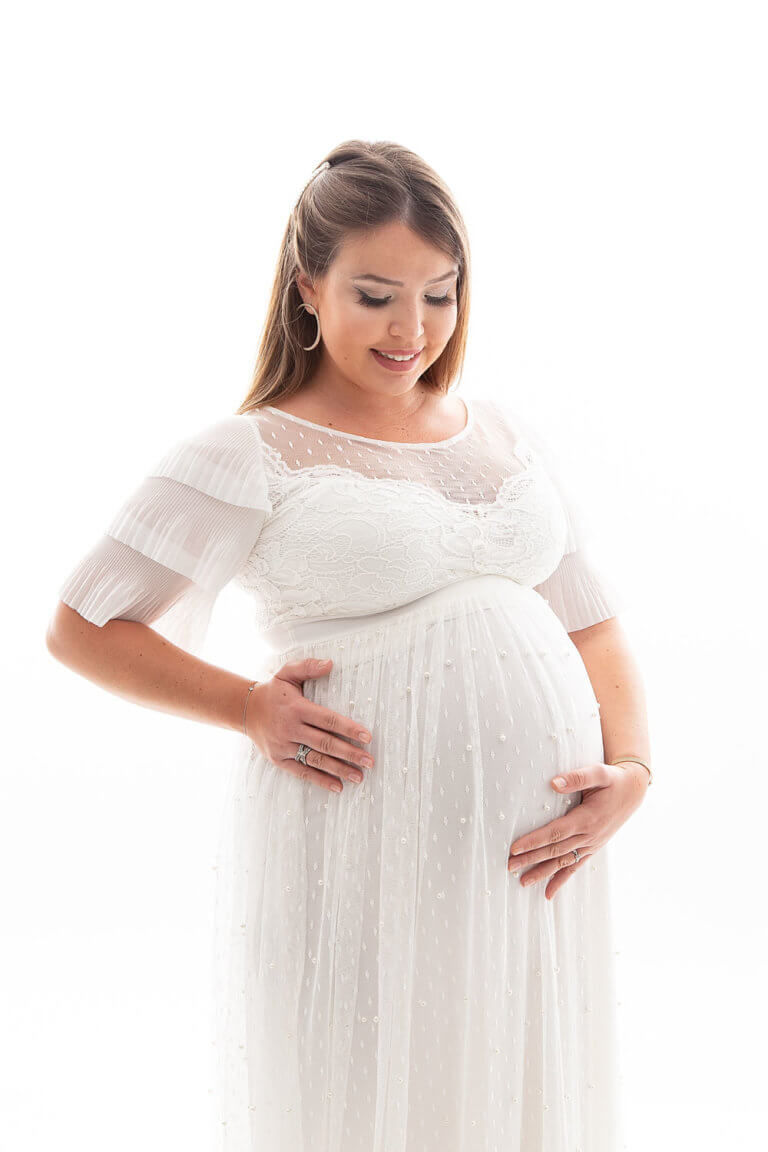 photos d une femme enceinte qui sourit avec une robe de grossesse blanche